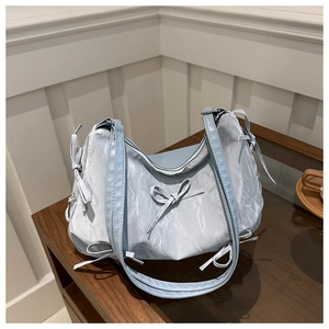 Détail du sac cabas bleu clair avec texture plissée, nœuds en ruban et zip argenté