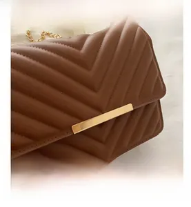 Detailed view of the brown chevron quilted leather and gold chain strap on the handbag