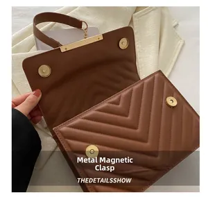 Detail of dark brown quilted shoulder bag with golden magnetic snap closure and V-stitch