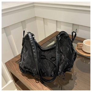 Détail du sac cabas froncé noir avec nœuds posé sur une table basse chic