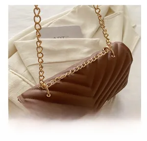Detail of brown quilted leather bag with chunky gold chain strap and stitching