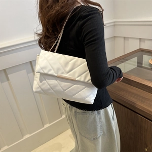 Minimalist white quilted shoulder bag with gold metal clasp and chain strap on a model