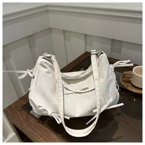 Détail du sac ivoire avec texture plissée et accents délicats de nœuds élégants