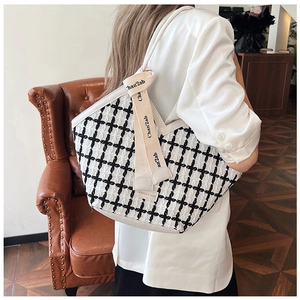 Detail of tweed tote bag with black and white check pattern and beige ribbon bow accent
