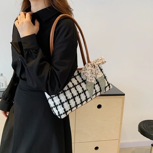 Chic black and white tweed tote bag with brown leather straps and floral bow accent