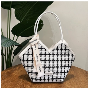 Detail of black and white tweed tote bag with V-shaped opening and stylish ribbon handle
