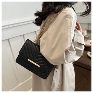 Detail of black V-quilted shoulder bag with gold metal trim and elegant chain strap