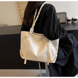 Cream tote bag with floral jacquard texture and woven rope straps shown in a cafe