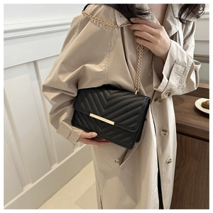 Detail of black V-quilted leather crossbody bag with elegant gold chain strap and metal clasp