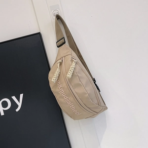 Detail view of khaki nylon crossbody bag with letter embroidery and adjustable strap