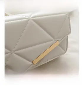 Macro shot of white quilted shoulder bag featuring premium texture and gold metal hardware