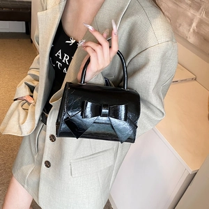 Glossy black patent leather handbag with bow detail and top handle for women