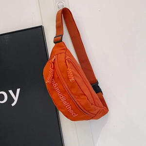 Detail view of orange nylon chest bag featuring textured letter printing and woven zipper pull