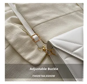 Detail of white quilted handbag showing golden adjustable buckle and swivel hook