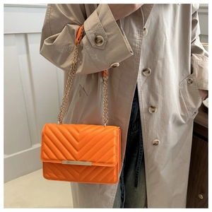 Shoulder bag in bright orange with chevron quilting and gold chain strap detail