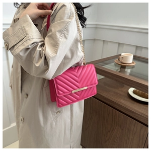 Detail of rose pink chevron quilted leather crossbody bag with gold metal chain strap