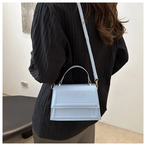 Close-up of light blue small square bag with geometric stitching and metal hardware