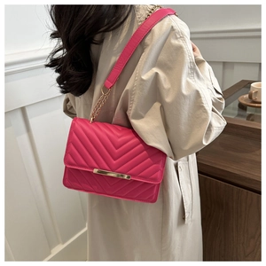 Close-up of fuchsia quilted shoulder bag with gold chain strap and metallic buckle