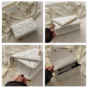 Detail view of white quilted square crossbody bag with gold metal trim and interior space