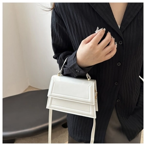 Close-up of white minimalist square bag with geometric stitching and metal hardware