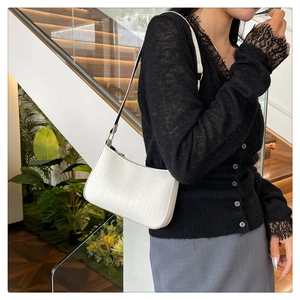 Detail of white crocodile pattern shoulder bag with slim strap in a minimalist style