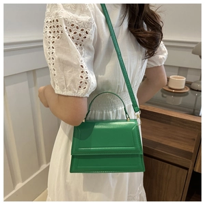 Detail view of emerald green leather handbag featuring golden hardware and refined stitching