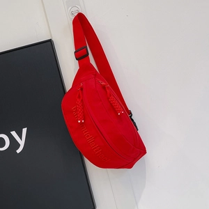 Detailed close-up of a red nylon crossbody bag showing the embroidered text and dual zippers