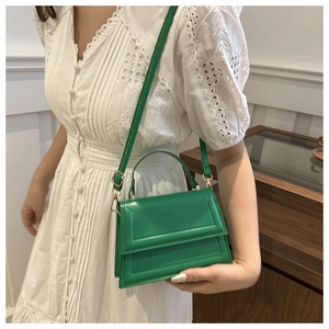 Detailed macro view of vibrant green PU leather texture and flap design on crossbody bag