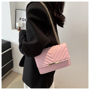 Detail of pink chevron quilted crossbody bag with gold metal trim and chain strap