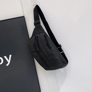 Detail of minimalist black nylon chest bag with woven zipper puller and side embroidery