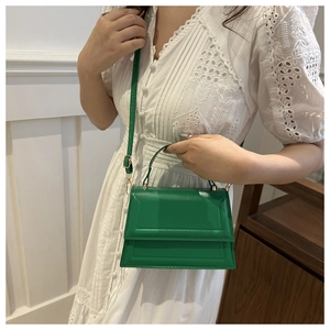Detailed close-up of a green mini square crossbody bag on a white dress model