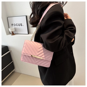 Pink quilted shoulder bag with gold chain strap shown on model in black blazer