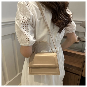 Detail of beige leather small square bag with geometric embossing and top handle