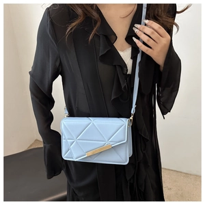 Detail of light blue crossbody bag with geometric quilting and gold metallic buckle
