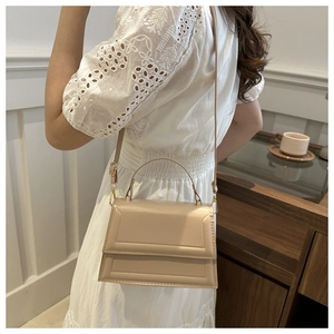 Detail of apricot crossbody bag showing elegant stitching and top handle on model