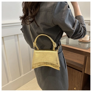 Detail view of golden hourglass handbag with faux crocodile skin texture and curved base