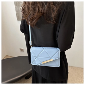 Detail of light blue quilted square bag with gold metal buckle and adjustable strap