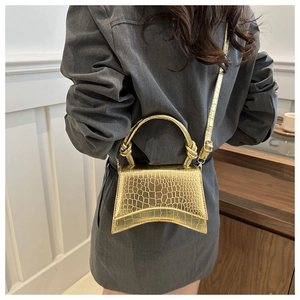 Detail of gold crocodile embossed leather handbag styled with a grey business suit
