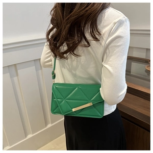 Detailed view of green quilted leather crossbody bag with gold metal trim and strap