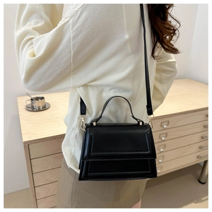 Detailed side view of structured black crossbody bag with adjustable shoulder strap
