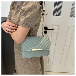 Detail of mint green crossbody bag featuring V-quilted faux leather and gold chain strap