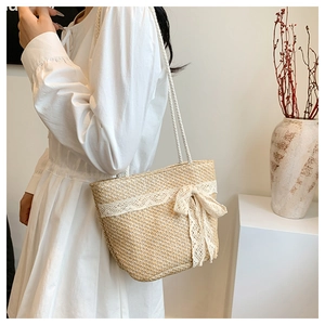 Detail of hand-woven straw tote bag featuring a delicate white lace bow and rope handles