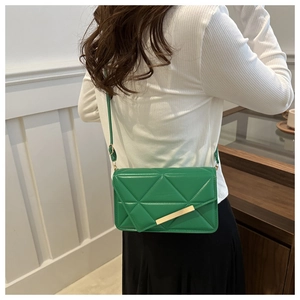 Close-up of green crossbody bag with geometric quilted pattern and gold metal trim detail