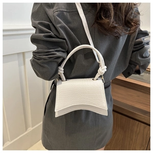 Close-up of white embossed crocodile texture and unique hourglass curved base on handbag