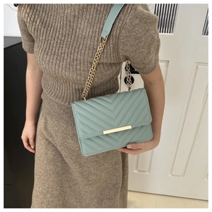 Detail view of mint green crossbody bag with V-chevron quilting and gold chain strap