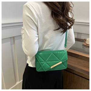 Detail of emerald green quilted crossbody bag with golden hardware and sleek finish