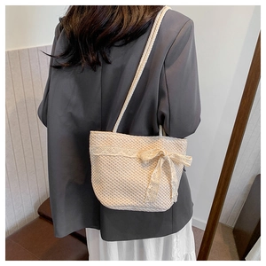 Detail of cream woven tote bag featuring delicate lace trim and sweet bow decoration