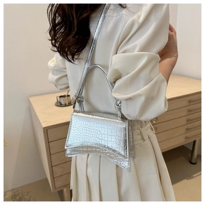 Detail of silver crocodile-embossed hourglass bag with glossy metallic finish and handle