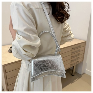 Detail of silver crocodile embossed texture on trapezoid handbag with knotted handle
