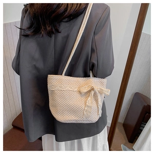 Close-up of beige woven straw tote bag with delicate lace trim and a central bow accent